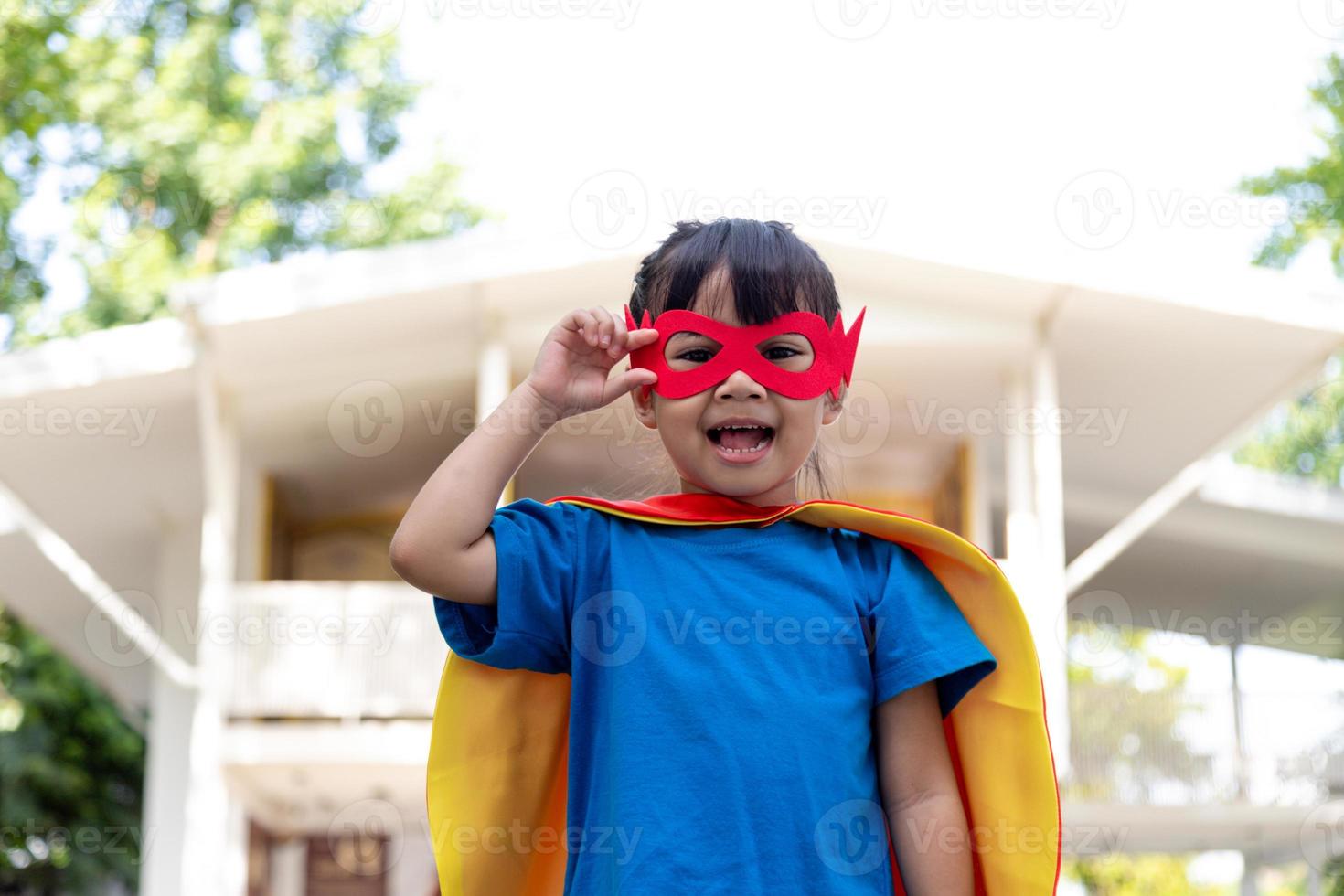 Little child girl plays superhero. Child on the white background. Girl power concept photo