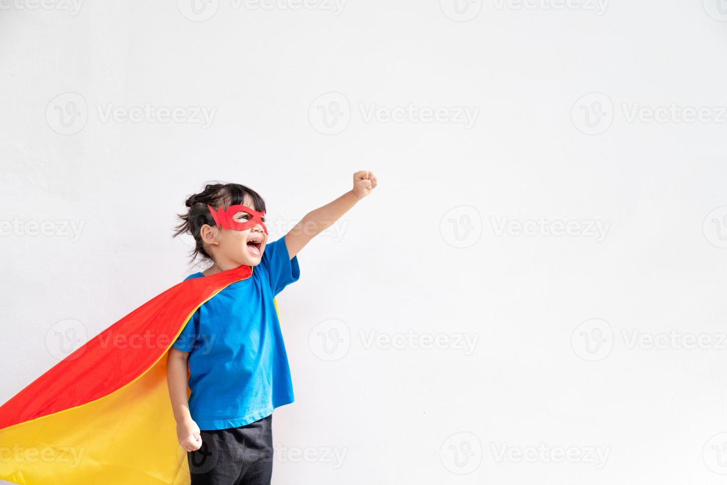 Funny little girl playing power super hero over white background. Superhero concept. photo