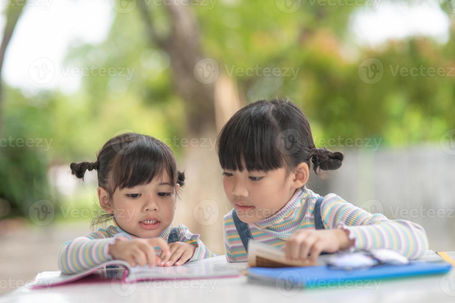 Two student little Asian girls reading the book on table photo