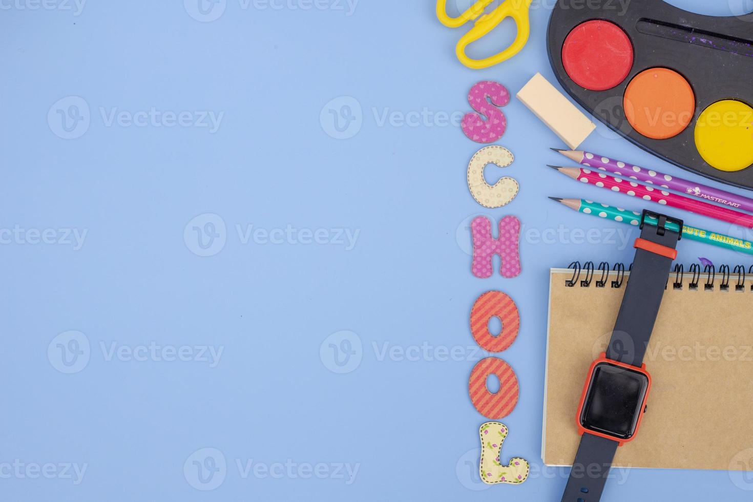 Stationery accessory on blue background. School supplies, pencils, paints, and color books, on blue background with copy space. Education and freelancer work concept photo