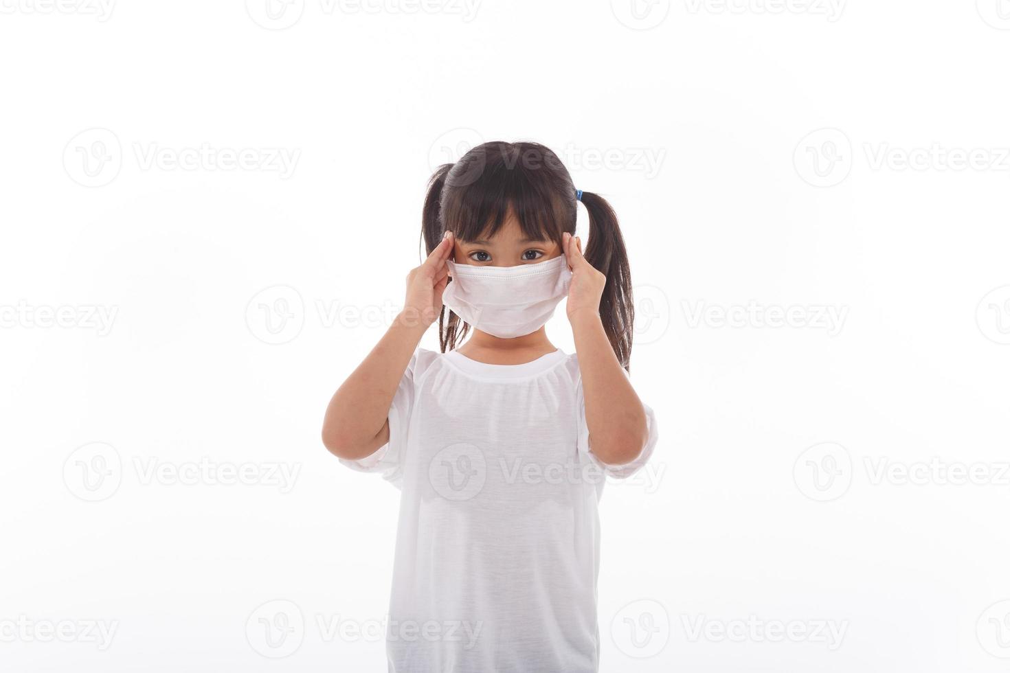 Asian child wearing a medical mask is feeling headache on white background. photo