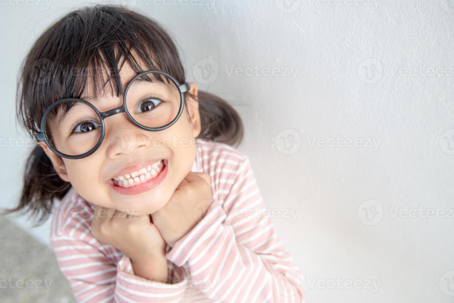 funny Asian child girl wearing glasses on a white background photo