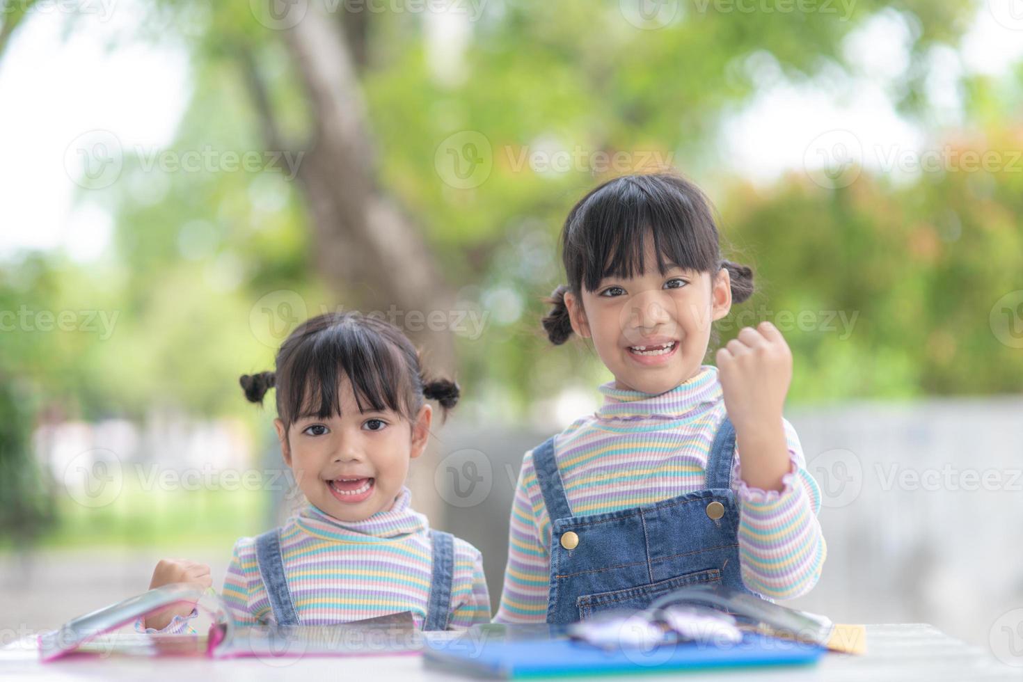 Two student little Asian girls reading the book on table photo