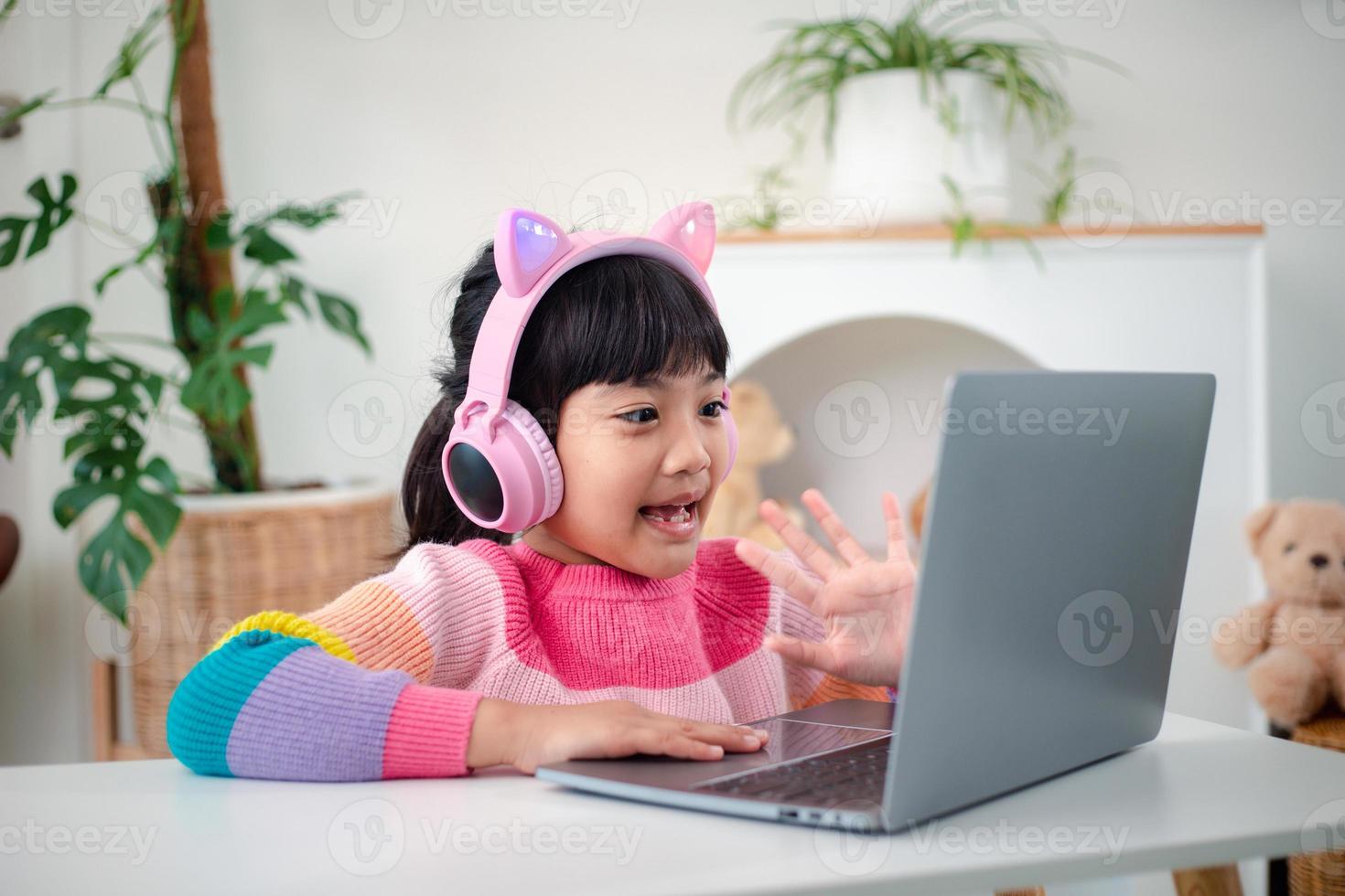 Smiling little Asian girl have a video call distant class with teacher using laptop, social distance during quarantine isolation during the Coronavirus photo
