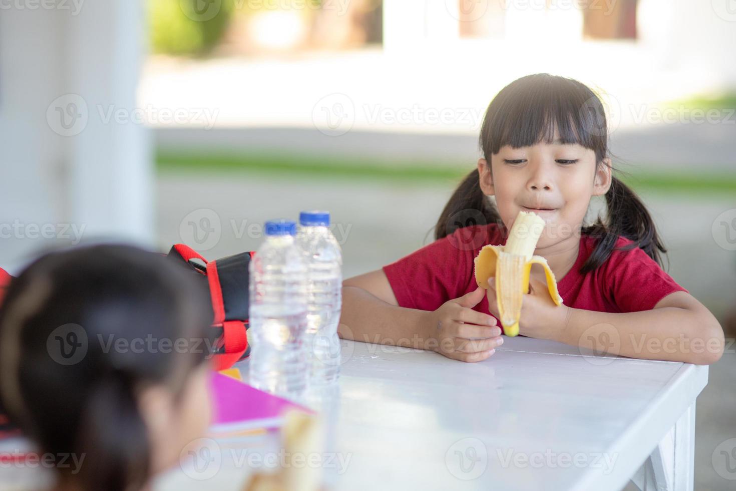 los niños asiáticos en la cantina almorzando o desayunando se divierten foto