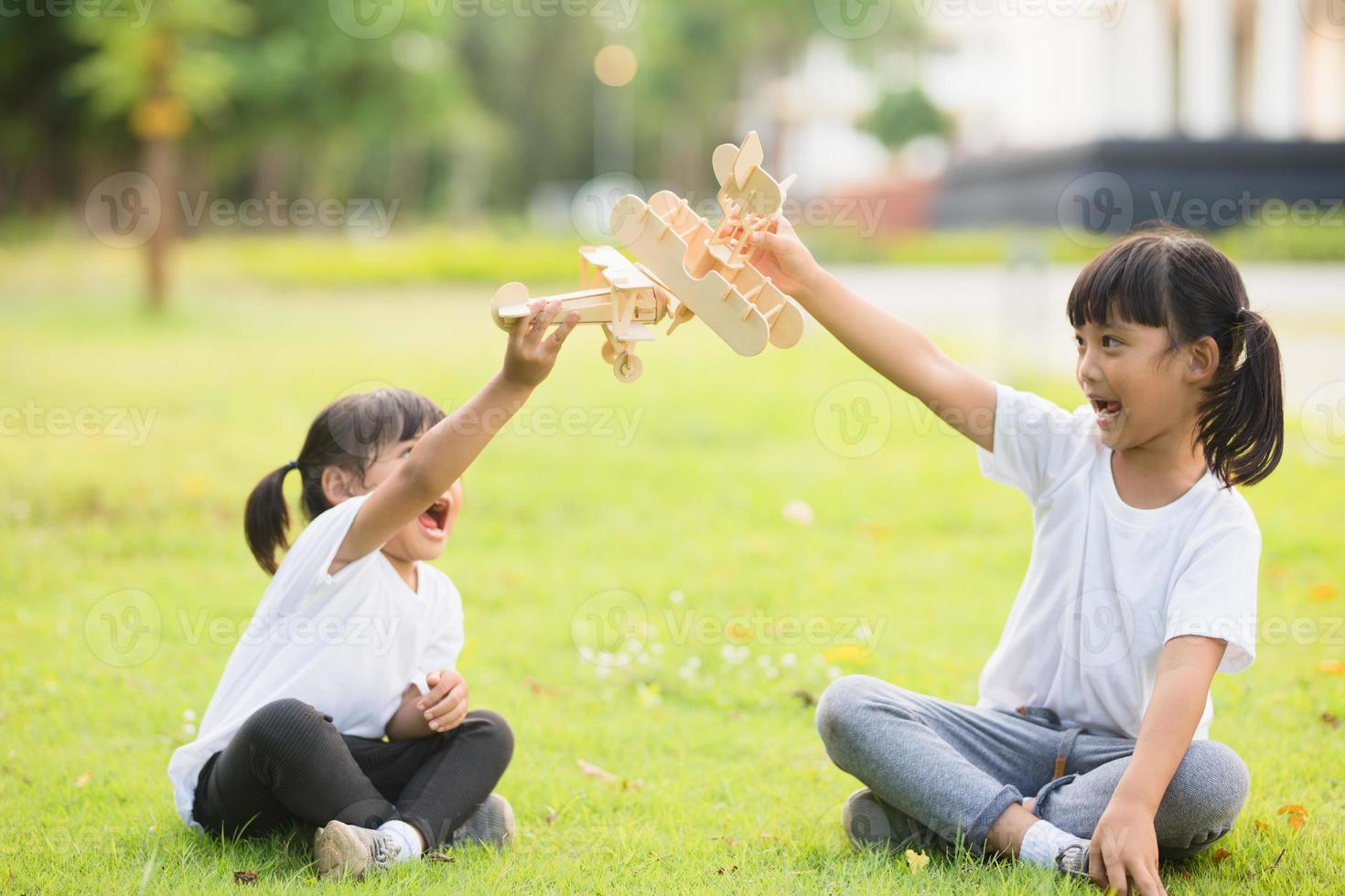 Two little kids playing with cardboard toy airplane in the park at the day time. Concept of happy game. Child having fun outdoors. photo