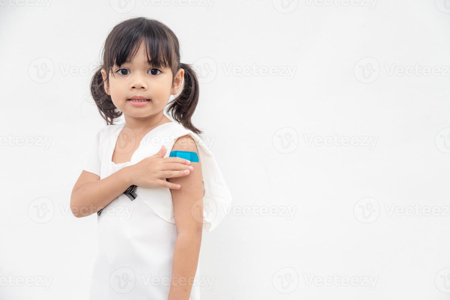 Asian little girl showing his arm after got vaccinated or inoculation, child immunization, covid delta vaccine concept photo