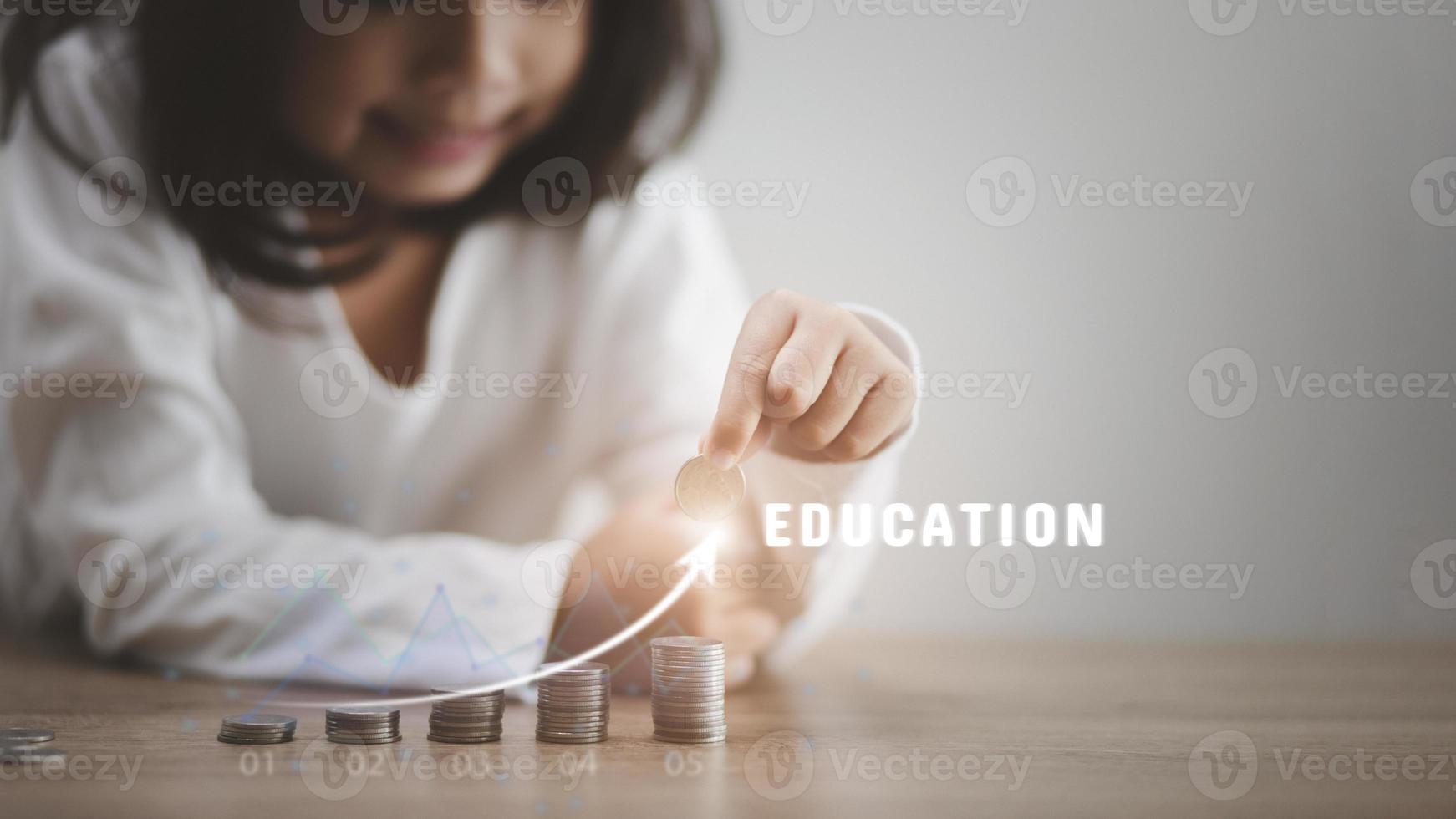 linda niña asiática haciendo montones de monedas. el niño ahorra dinero para la educación futura. concepto de dinero, finanzas y personas foto