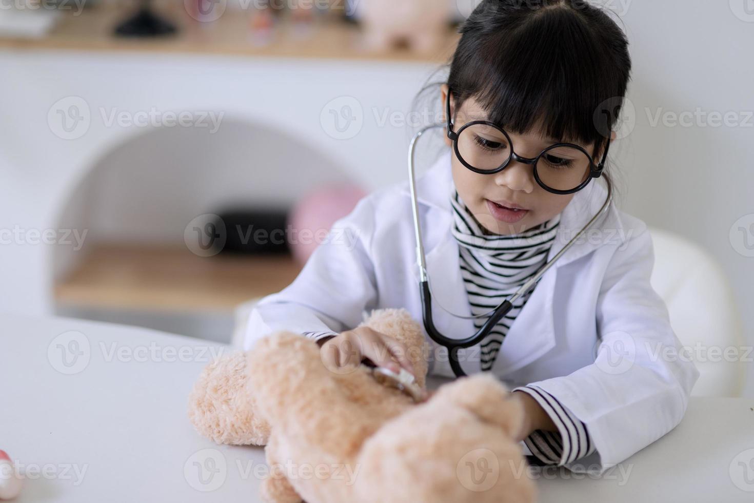 Asian girl playing with her patient plush bear in a doctor game, using a stethoscope. Children want to be a pediatrician doctor photo