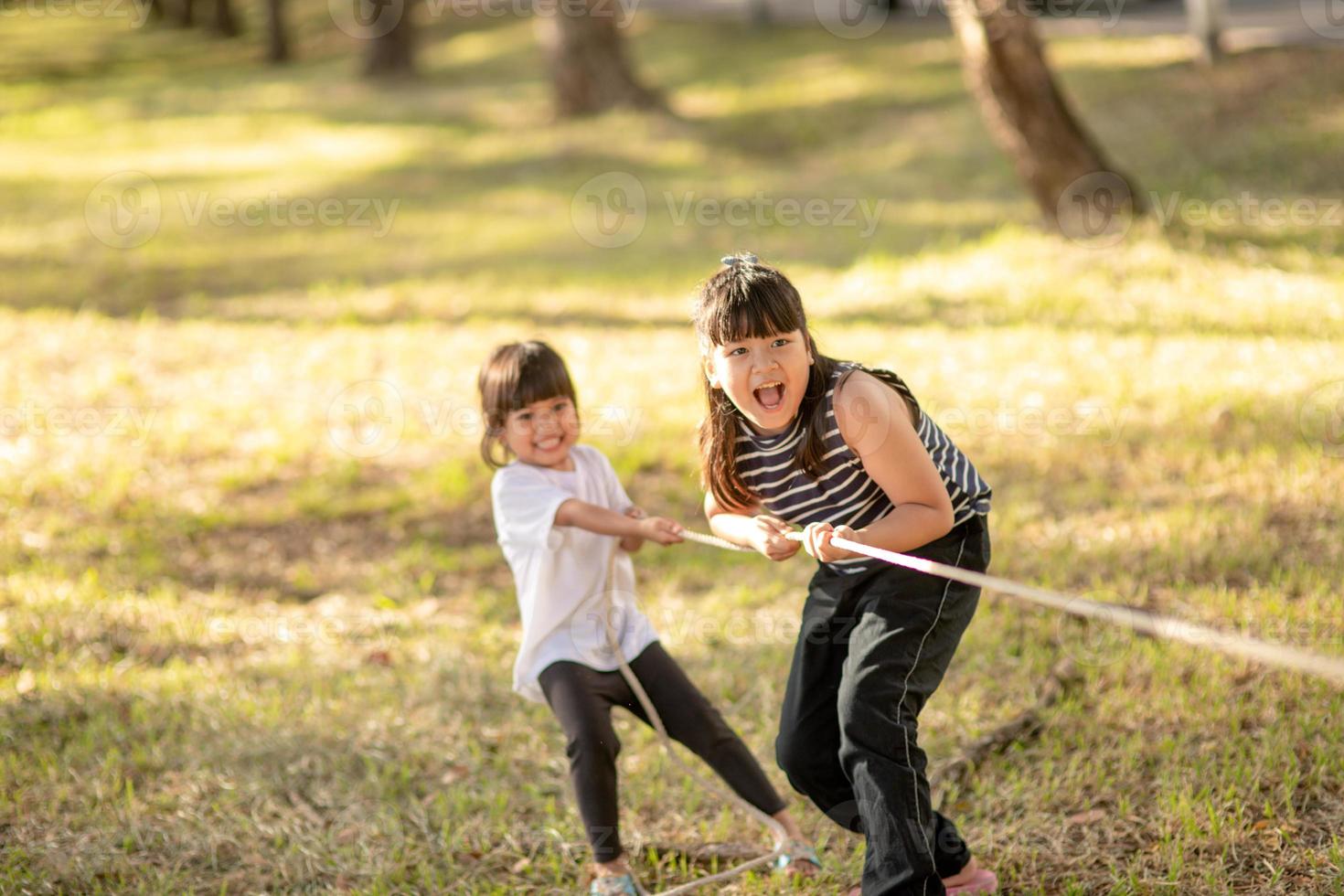 Children playing tug of war at the park on sunsut photo