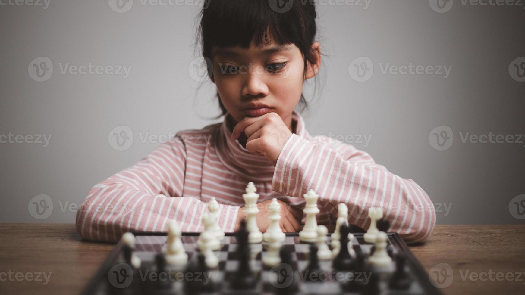 Little girl taking part in chess competition thinking over strategy, hobby photo