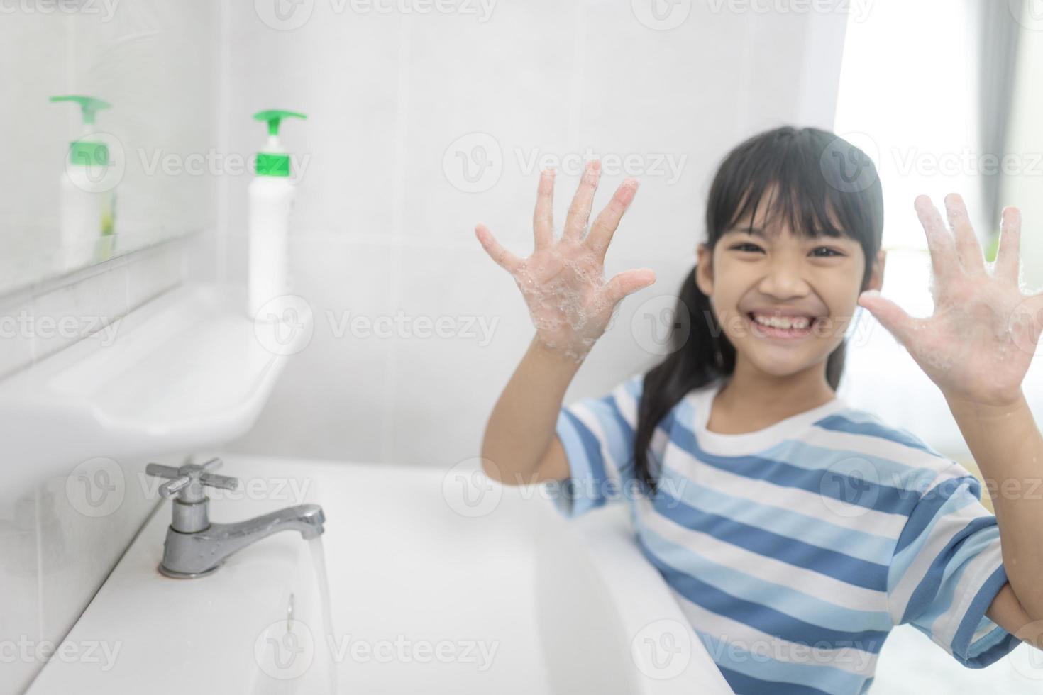 Little Asian girls wash their hands in the bathroom. Soft focus. Copy space. photo