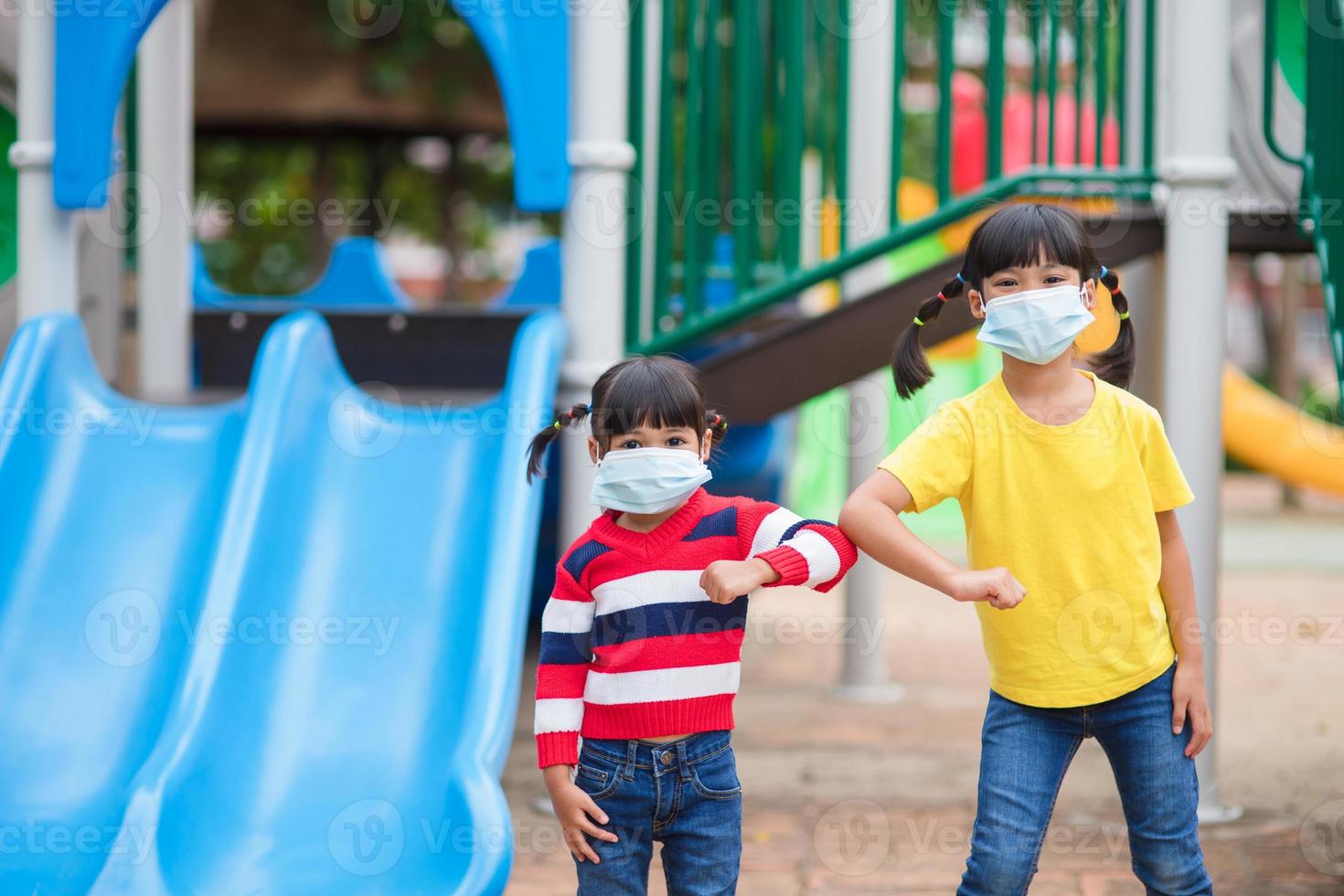 new normal lifestyle, social distancing concept. happy kids wearing face mask having fun on at playground protect coronavirus covid-19, photo