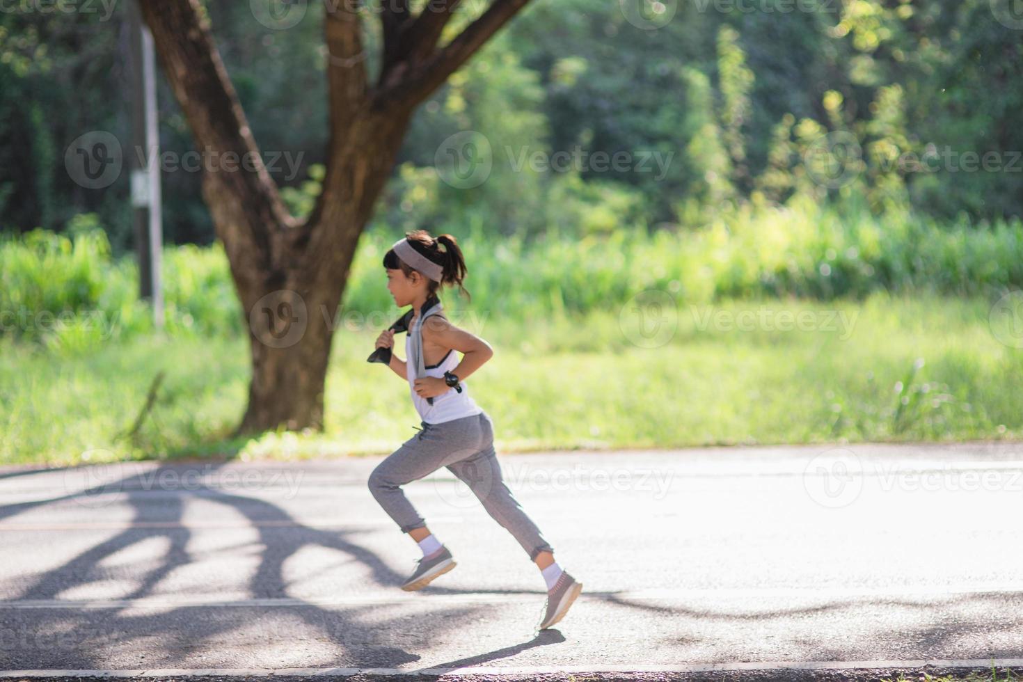 happy child girl running in the park in summer in nature. warm sunlight flare. asian little is running in a park. outdoor sports and fitness, exercise and competition learning for kid development. photo