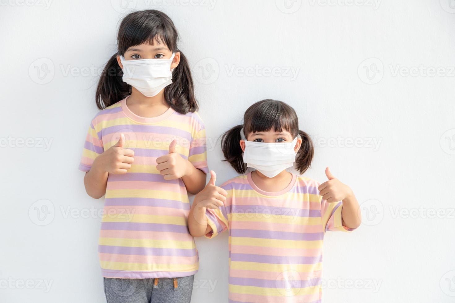 Sibling Little girl wearing a mask to stop coronavirus outbreak.Quarantine Asian sibling.Covid-19 coronavirus and pandemic virus symptoms. photo