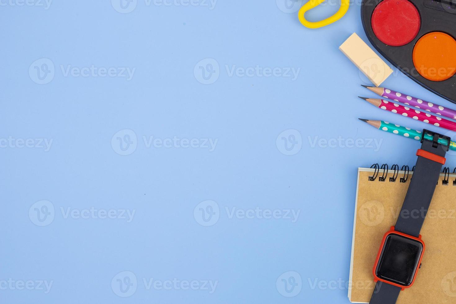Stationery accessory on blue background. School supplies, pencils, paints, and color books, on blue background with copy space. Education and freelancer work concept photo