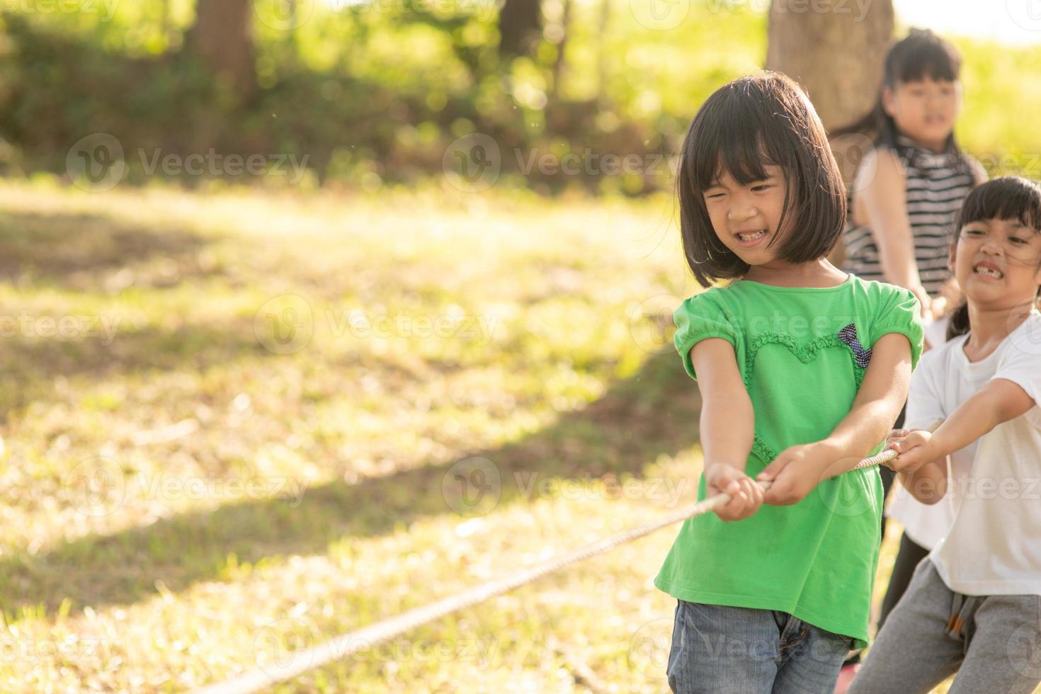 Children playing tug of war at the park on sunsut photo