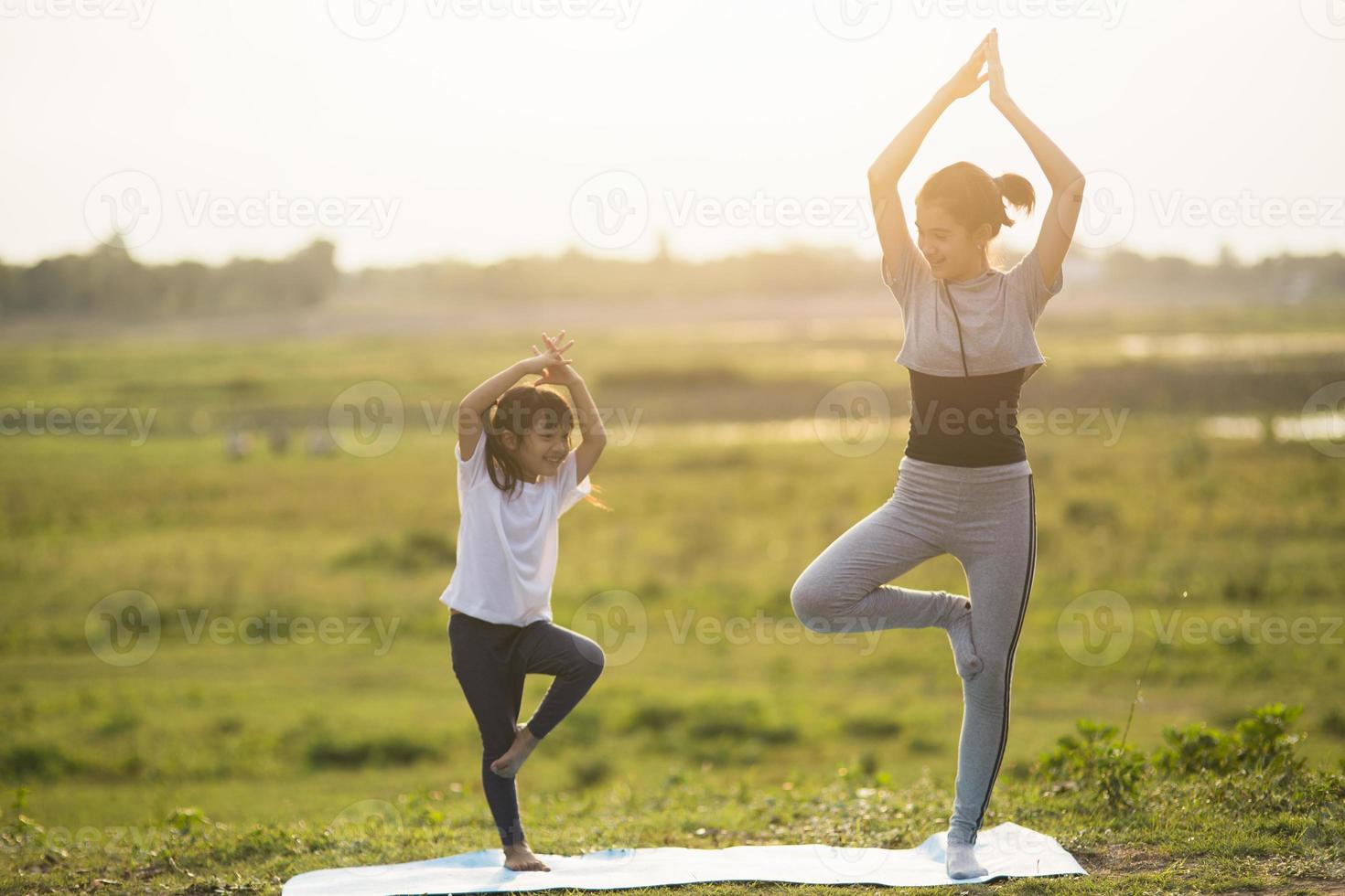 dos chicas lindas practicando yoga en el parque con luz brillante y soleada. foto