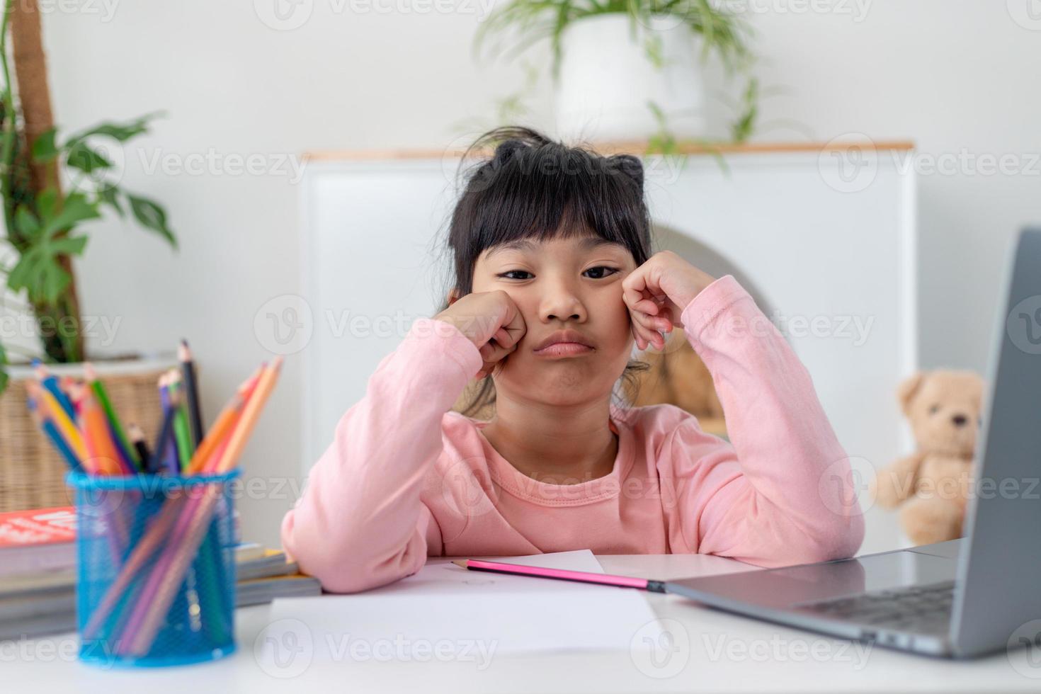 Unhappy little Caucasian girl child sit at table at home feel lazy unmotivated doing homework assignment. Upset distressed small 7s kid prepare school task, learn study with books. Education concept. photo