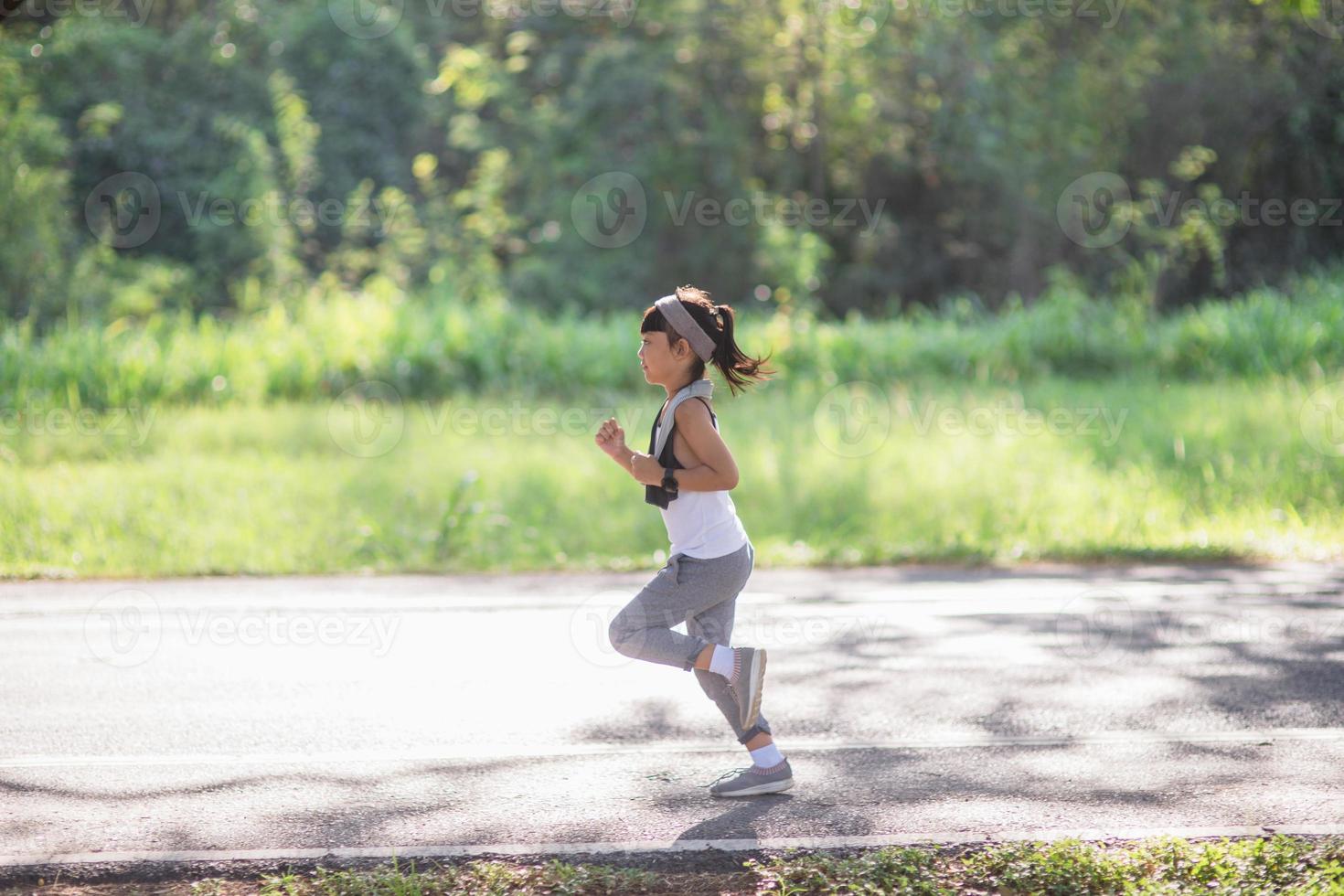 happy child girl running in the park in summer in nature. warm sunlight flare. asian little is running in a park. outdoor sports and fitness, exercise and competition learning for kid development. photo