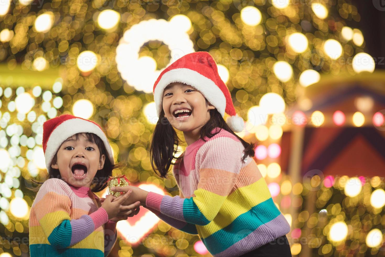 feliz navidad niños felices con un regalo mágico en casa cerca del árbol de navidad foto
