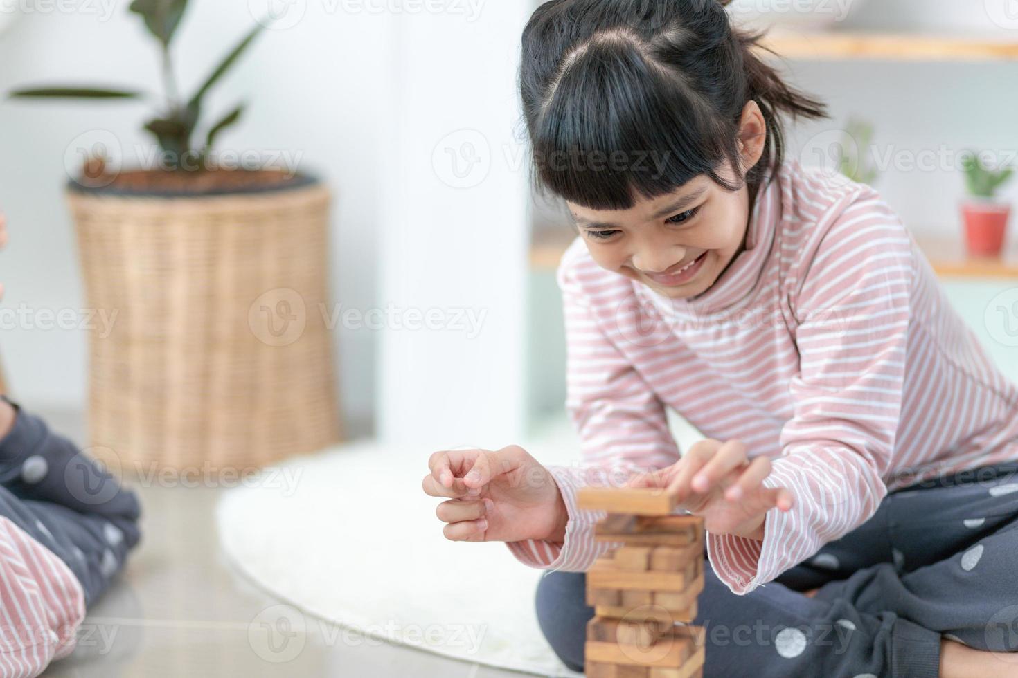 Asian sibling  girl playing wooden stacks at home photo