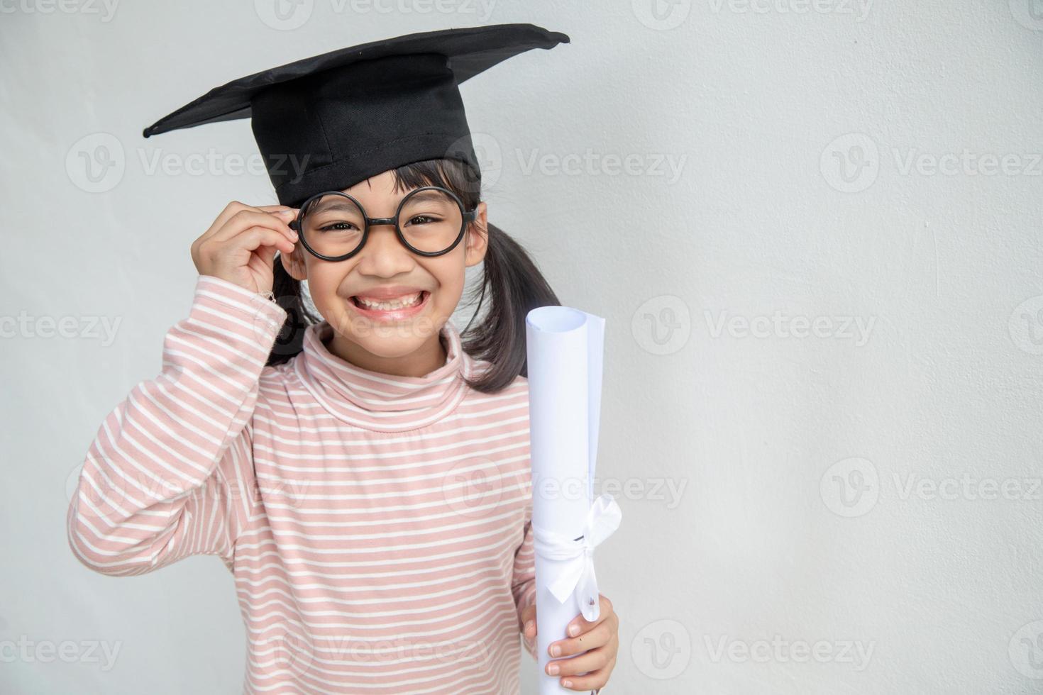 feliz niño de la escuela asiática graduado en gorra de graduación foto