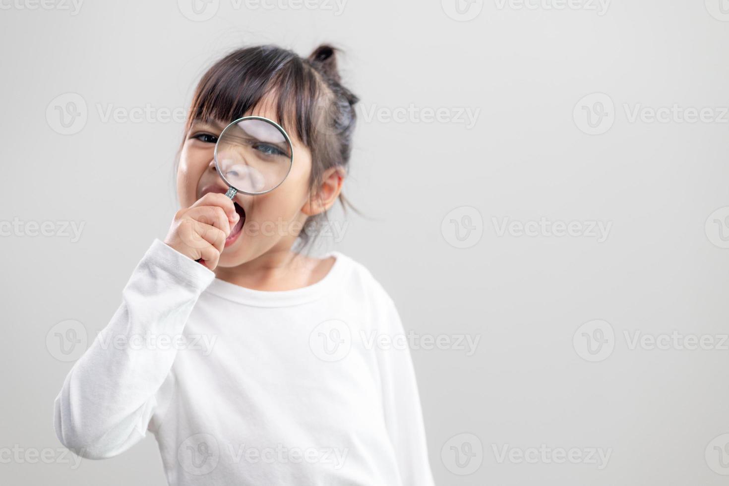 niña mirando a través de una lupa foto