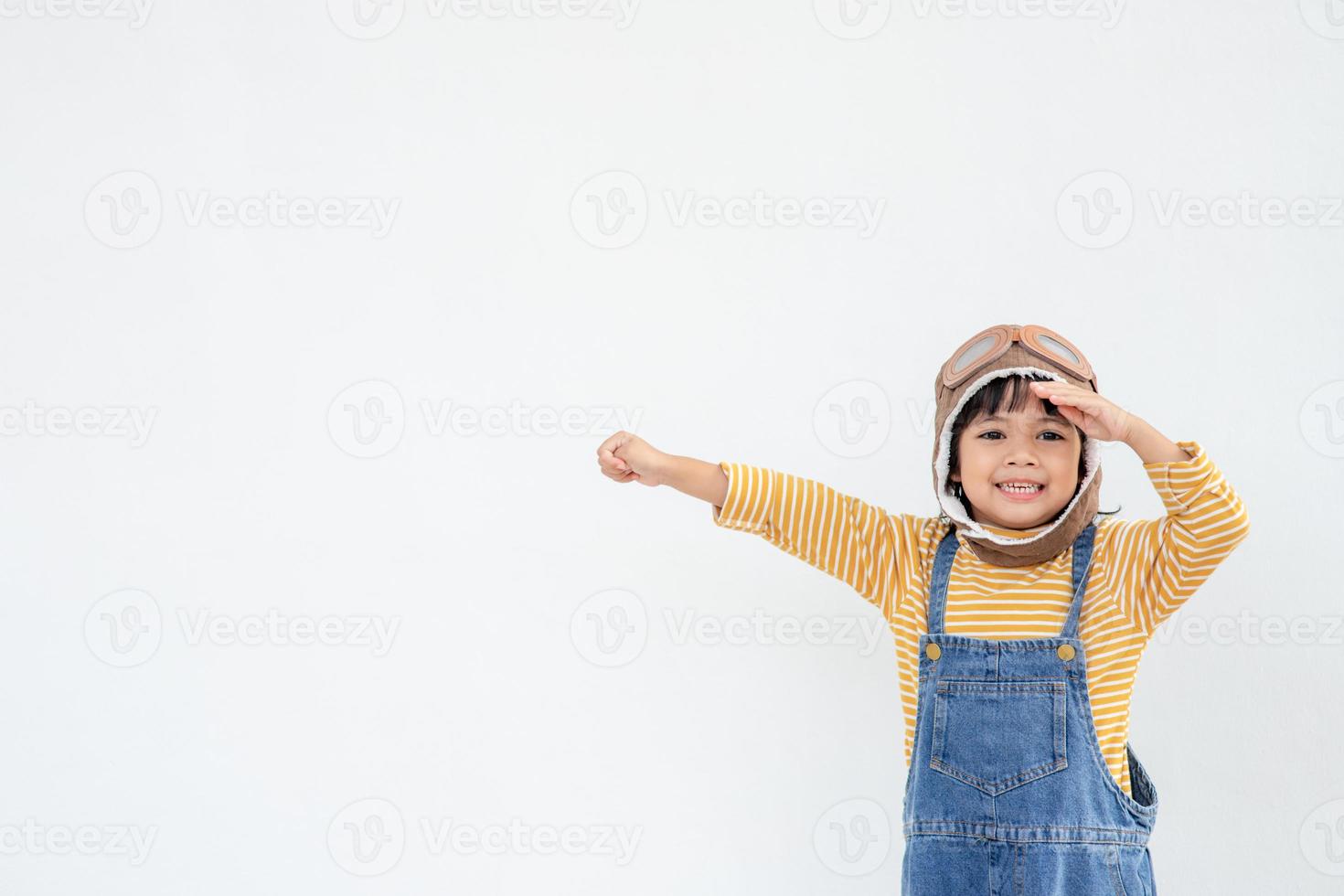 dreams of flight little child girl playing with a pilot hat on white background photo