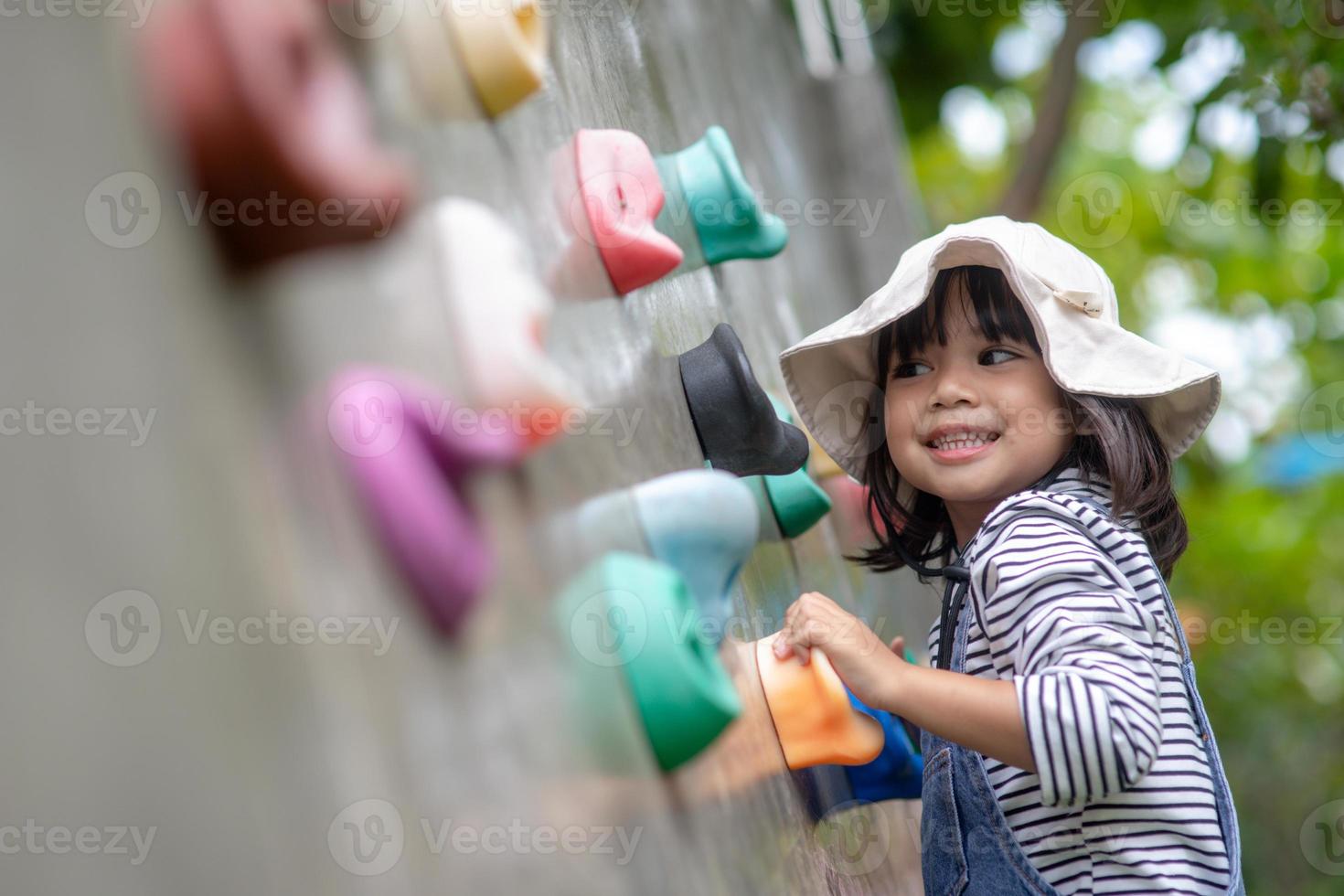 Asian little girl climbing a rock wall photo