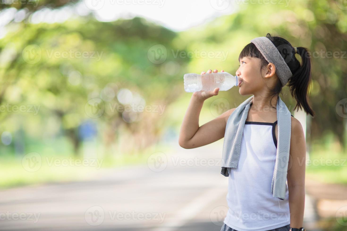 Cute asian girl drinks water from a bottle outdoors  with sunllight photo