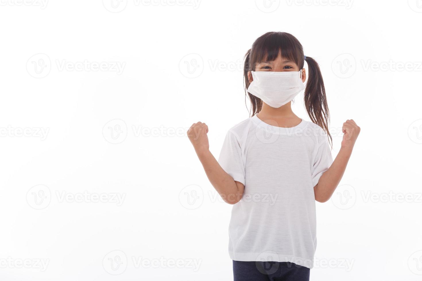 asia girl wearing mask to protect against Coronavirus, girl show a fist encourage to fight contagious disease concept stop virus Covid 19 outbreak to win on white background photo