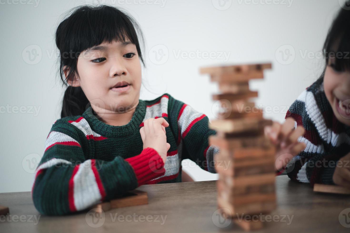 Cheerful Asian girl playing with wooden building blocks. Having fun and learning creativity. smart kid concept. photo