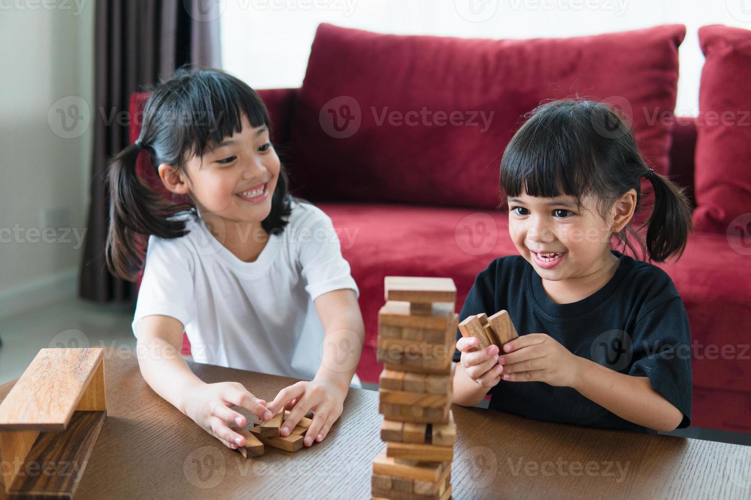 two Asian girl playing wooden stacks at home photo