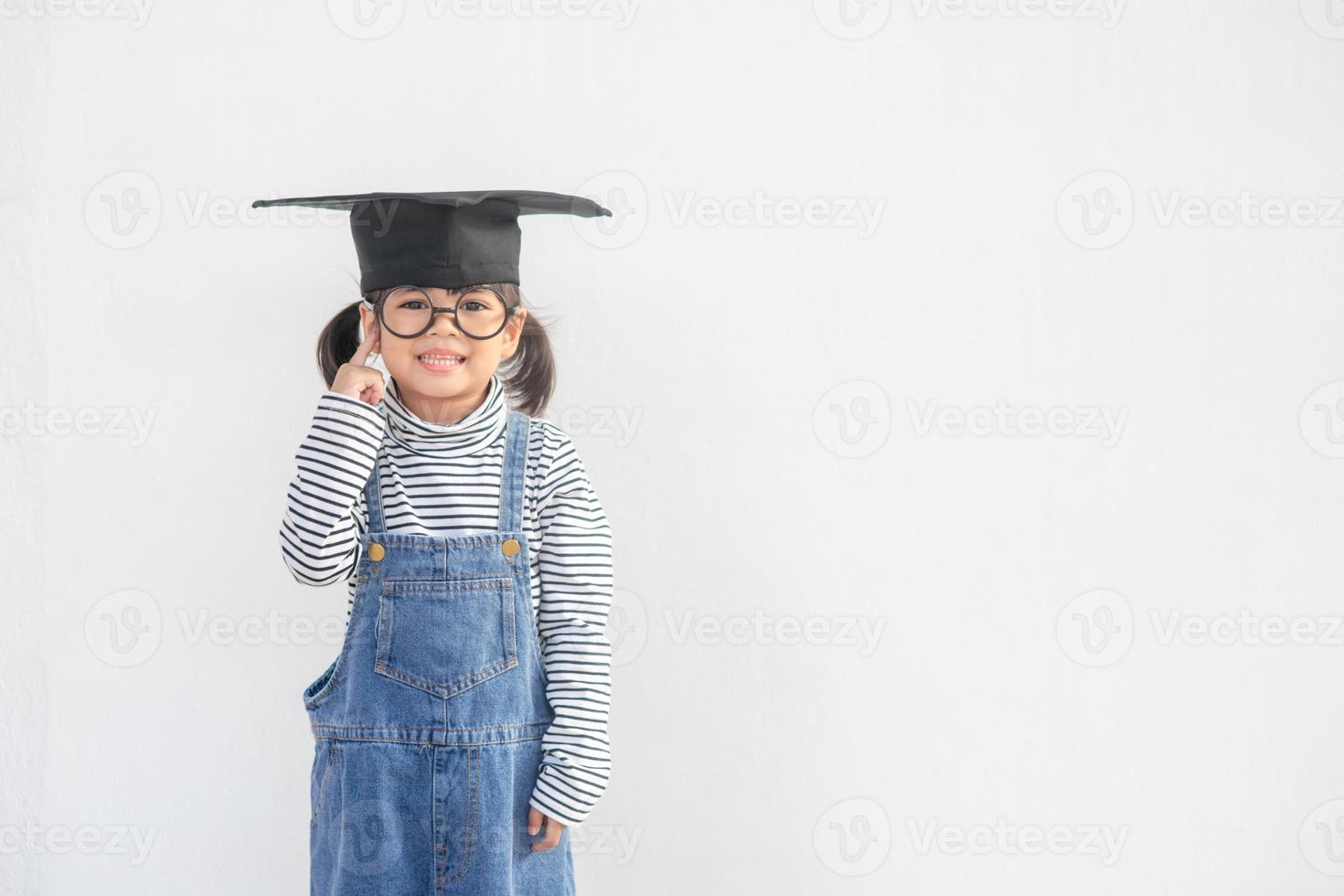 Happy Asian school kid graduate thinking with graduation cap photo