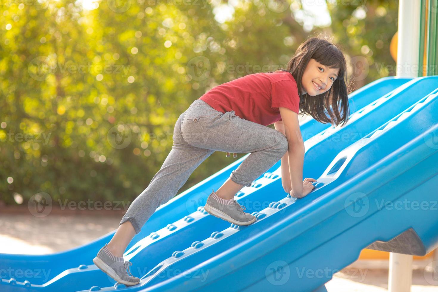 Cute little girl having fun on a playground outdoors in summer photo