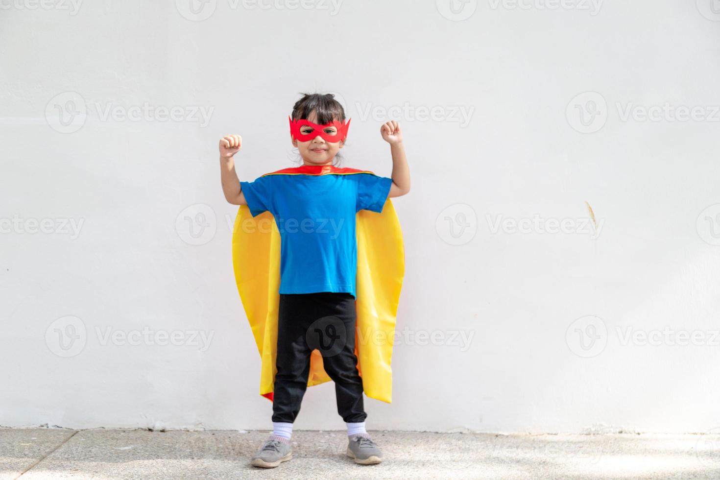 niña pequeña juega superhéroe. niño sobre el fondo blanco. concepto de poder femenino foto