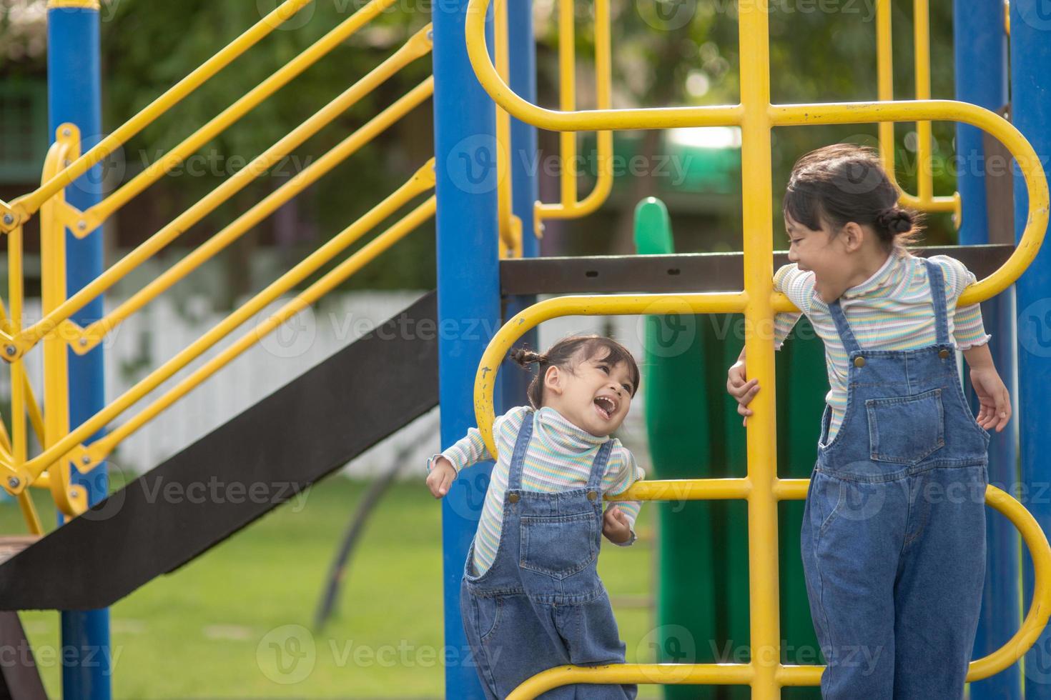 Cute little girls siblings having fun on playground outdoors on a sunny summer day. active sport leisure for kids photo