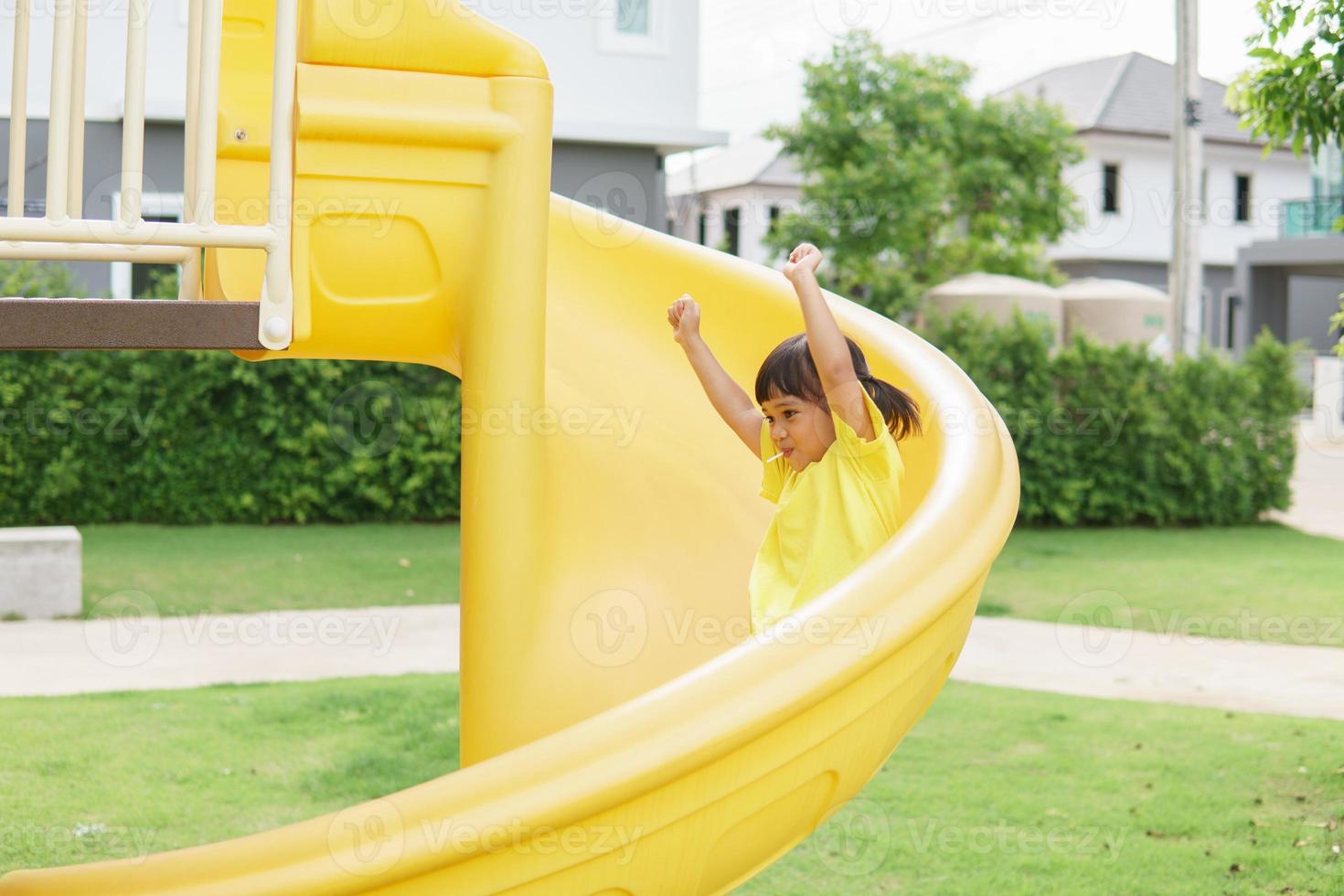 Child playing on outdoor playground. Kids play on school or kindergarten yard. Active kid on colorful slide and swing. Healthy summer activity for children. photo