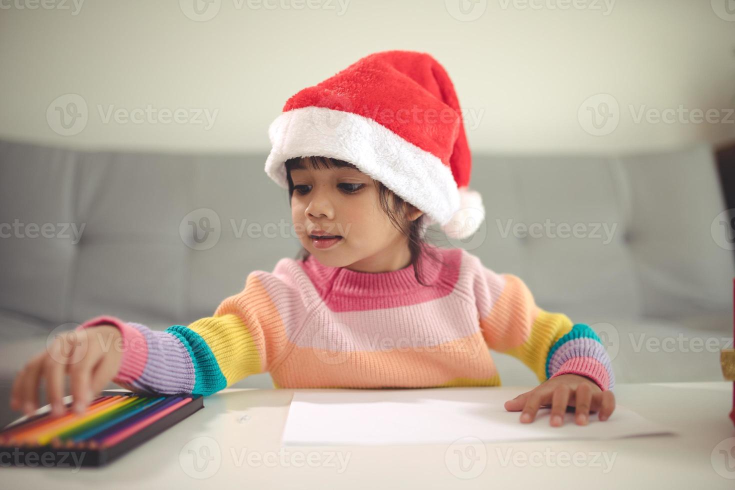 Christmas Child Write Letter to Santa Claus, Kid in Santa Hat Writing Wish List photo