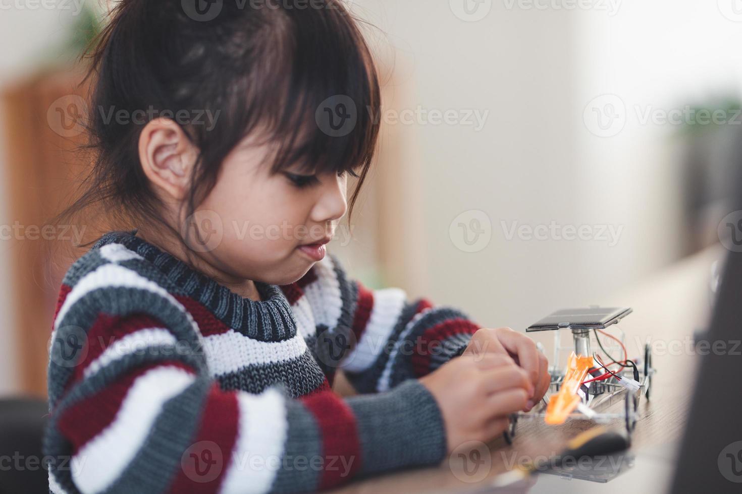 Inventive kid constructing robot cars at home photo