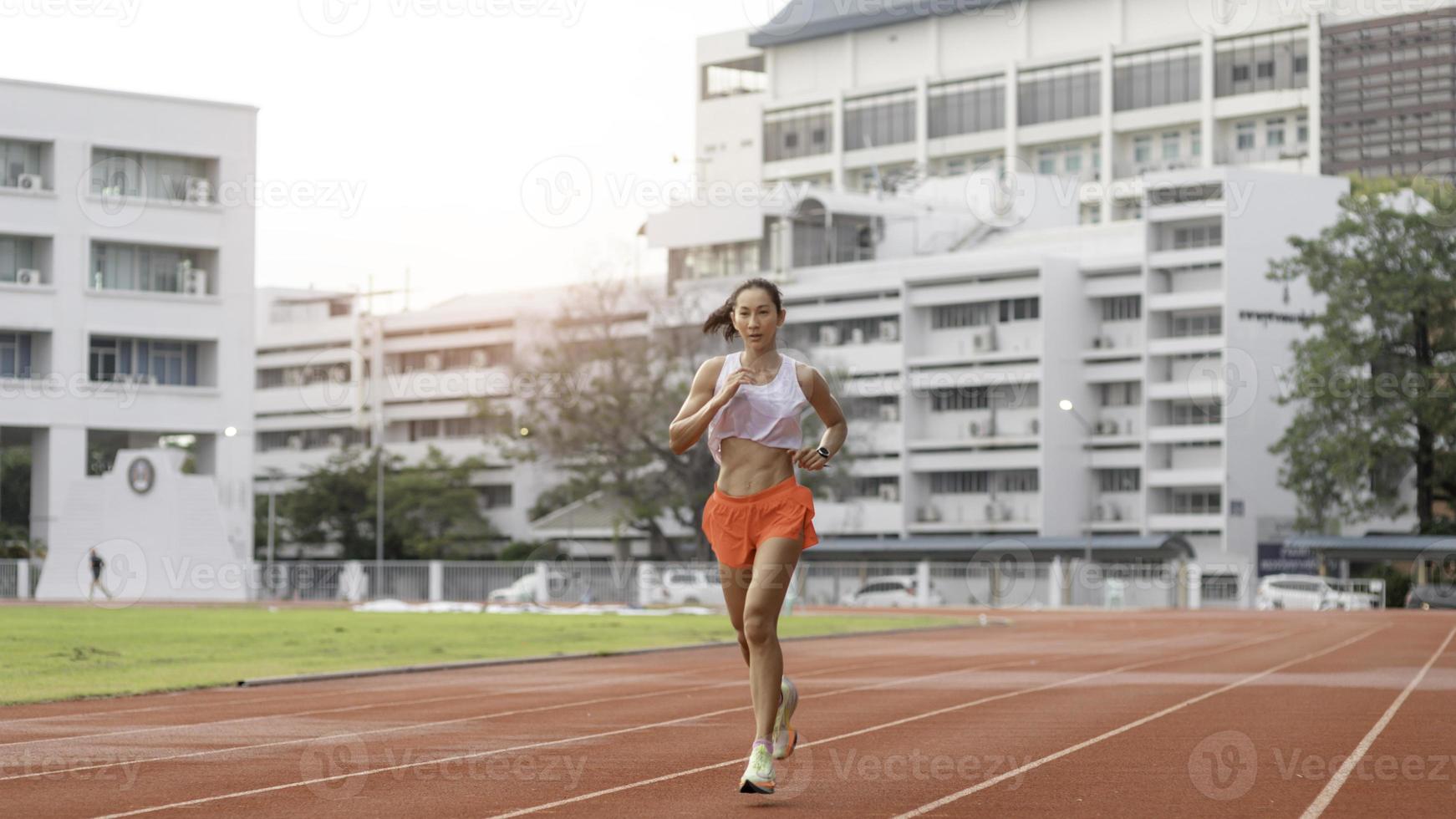 mujer corriendo durante la mañana soleada en la pista del estadio foto