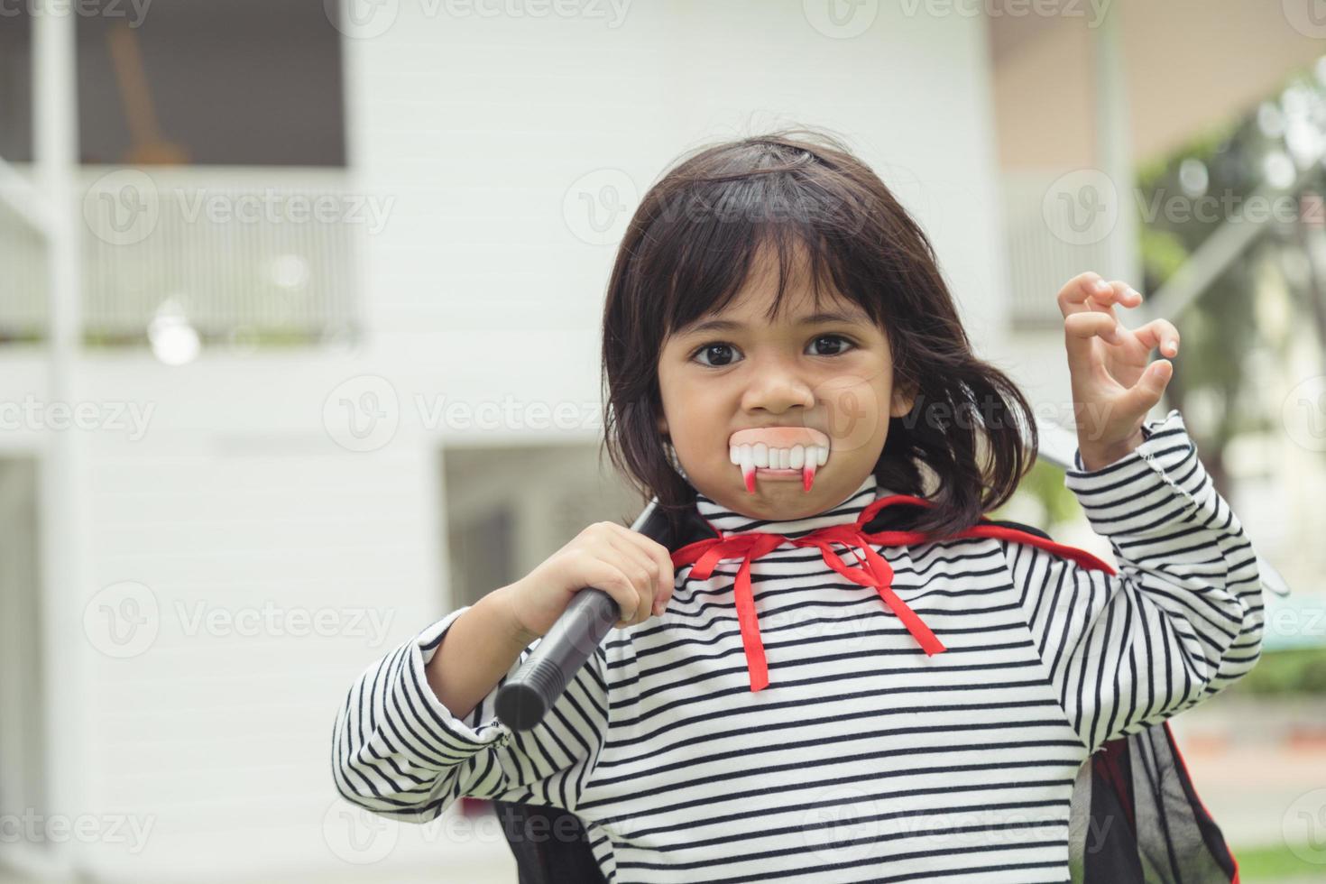 Children girl wearing mysterious Halloween dress holding a sickle on white background photo