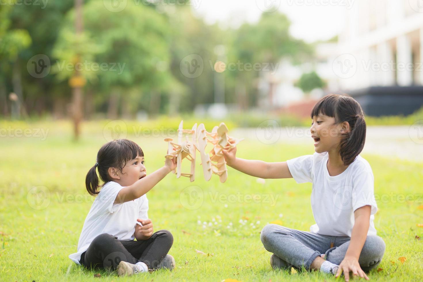 dos niños pequeños jugando con un avión de juguete de cartón en el parque durante el día. concepto de juego feliz. niño divirtiéndose al aire libre. foto