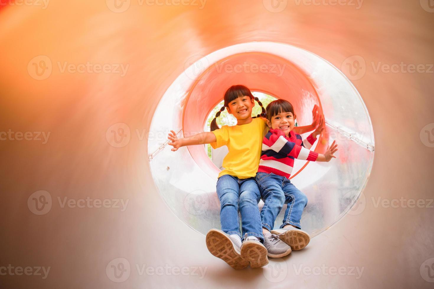 Cute little girls siblings having fun on playground outdoors on sunny summer day photo