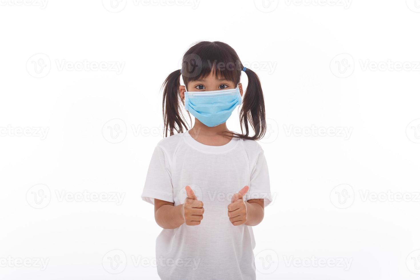 Little asian girl wearing mask for protect pm2.5 and show thumbs up gesture for good air outdoor.Air pollution pm2.5 and Coronavirus concept photo