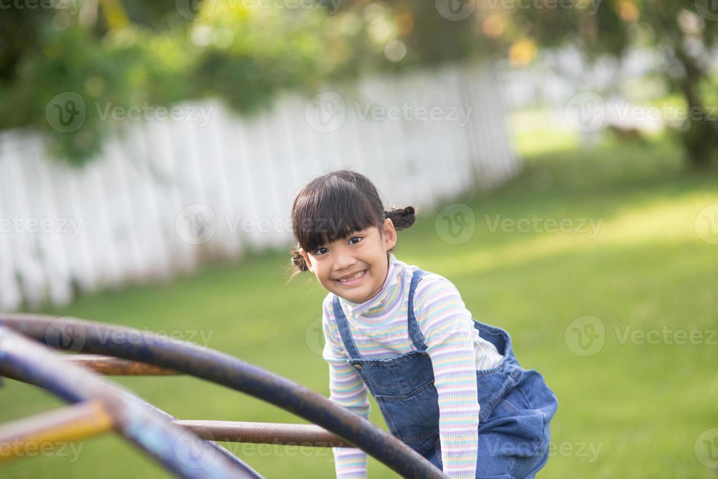 Asian Child girl playing on the outdoor playground. Kids play in school or kindergarten yard. Healthy summer activity for children. photo