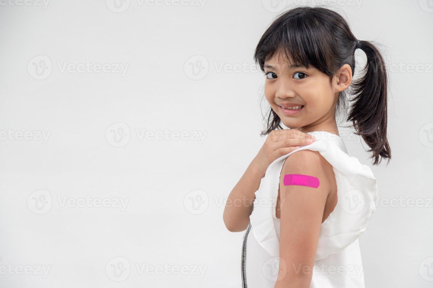 niña asiática mostrando su brazo después de ser vacunada o inoculada, inmunización infantil, concepto de vacuna covid delta foto