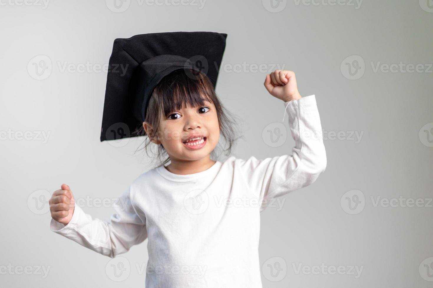 Happy Asian school kid graduate in graduation cap photo