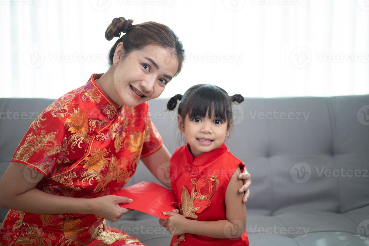 happy Asian little girl received red envelope from mother for Chinese new year photo